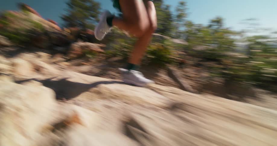 Woman running along a trail between rocks in the mountain