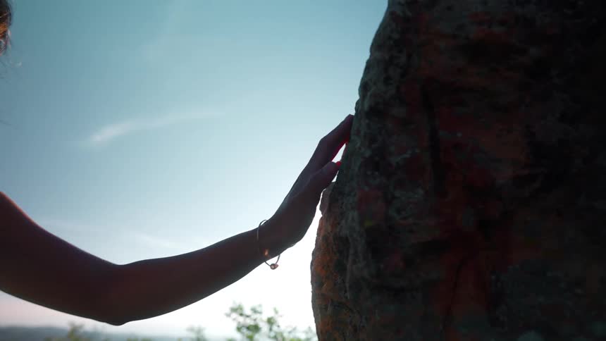 The girl touches the boulder on a windy day