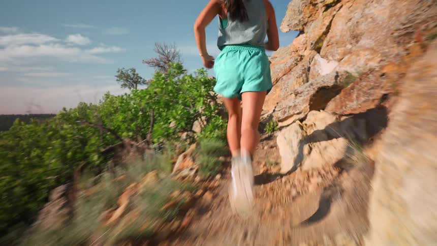 The woman runs fast on the thin mountain trail