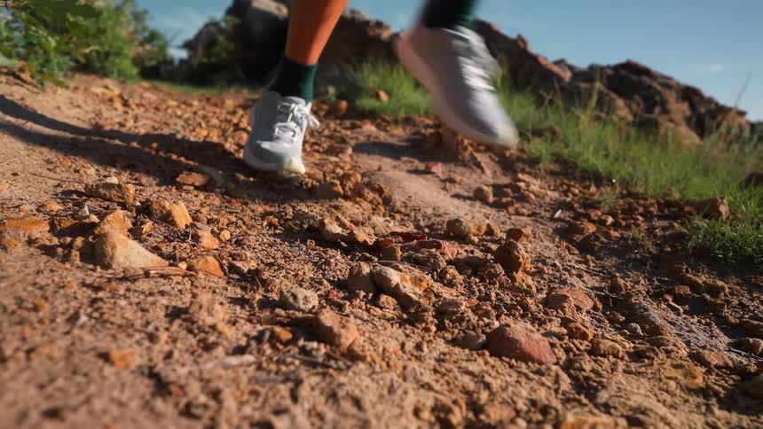 Closeup of a person jogging on a rocky trail on a summer day