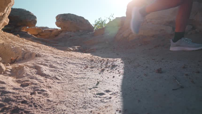 A woman runs down the path on the sunny mountain