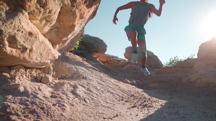 The woman jumps and runs down the mountain trail