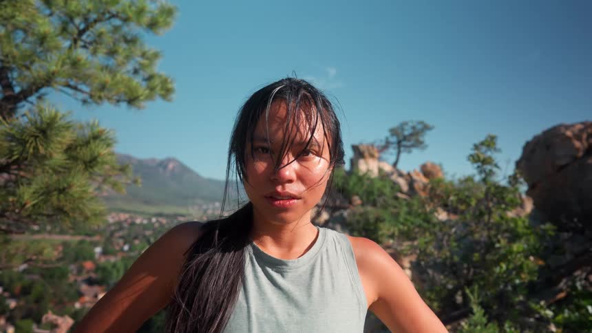 Woman catching breath after hike standing against mountain backdrop