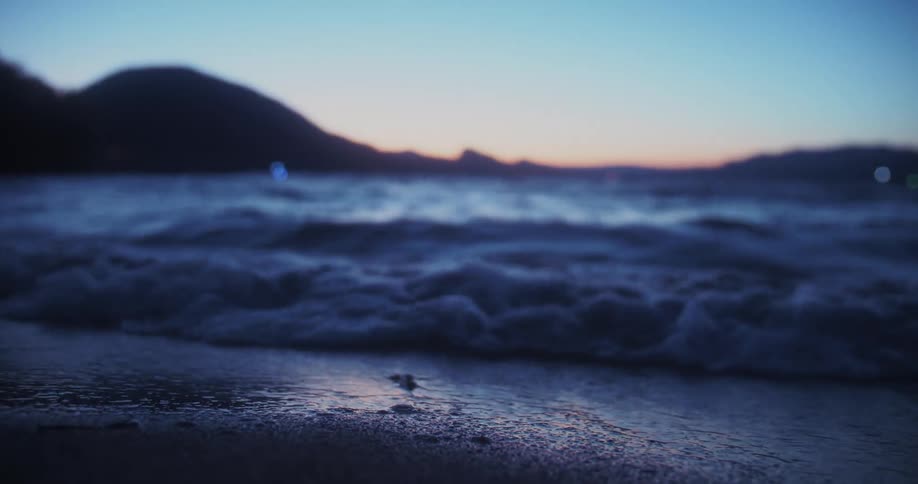 Close up of a beach area at sunset as water waves flow over continuously