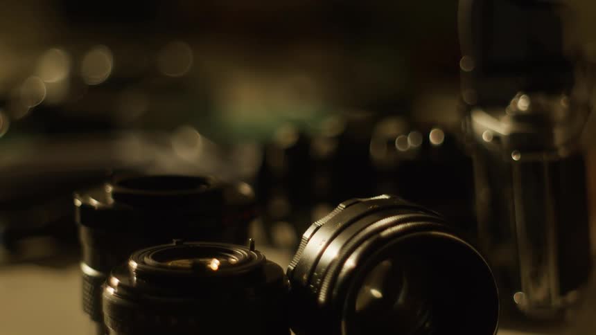 Close up of dismantled camera lenses places on a surface beside a camera