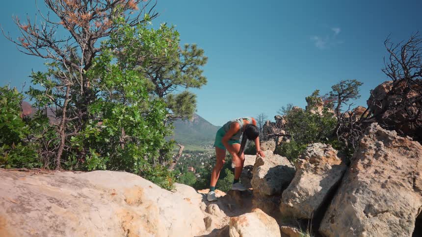 A woman is happy and breathing hard after running to the peak of the mountain
