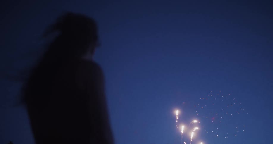 The woman watches the fireworks at night