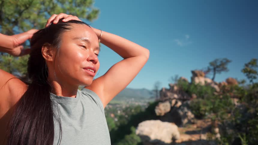 Woman on a trail running her hand through her face and hair