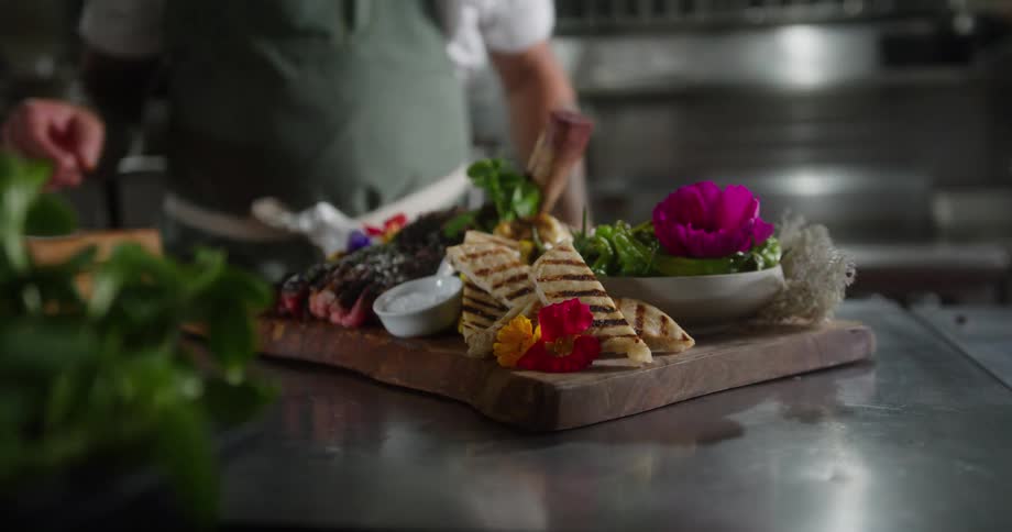 The man is plating a meal in the kitchen