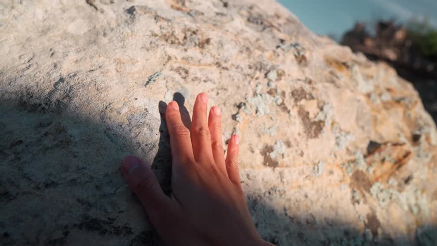 Hand being passed on a rock of a mountain