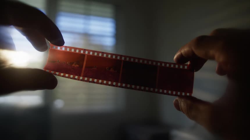 Black hands holding a piece of film in the air