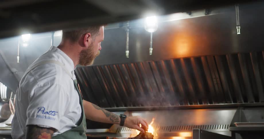 A chef grills a steak on a grill in the kitchen