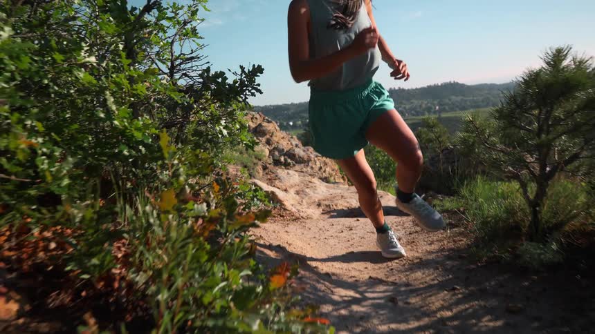 The woman runs by the edge of the cliff on a sunny day