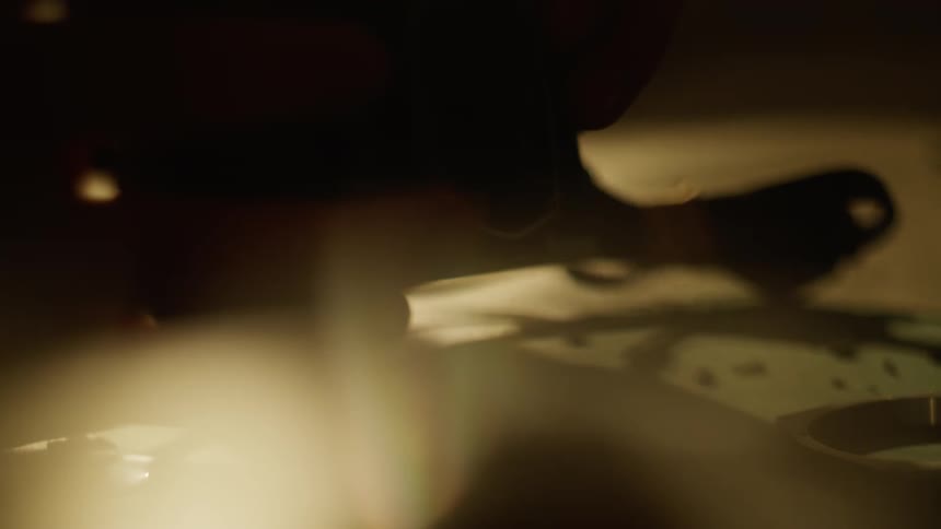 Close up of a person picking up a dismantled camera from a table surface indoors
