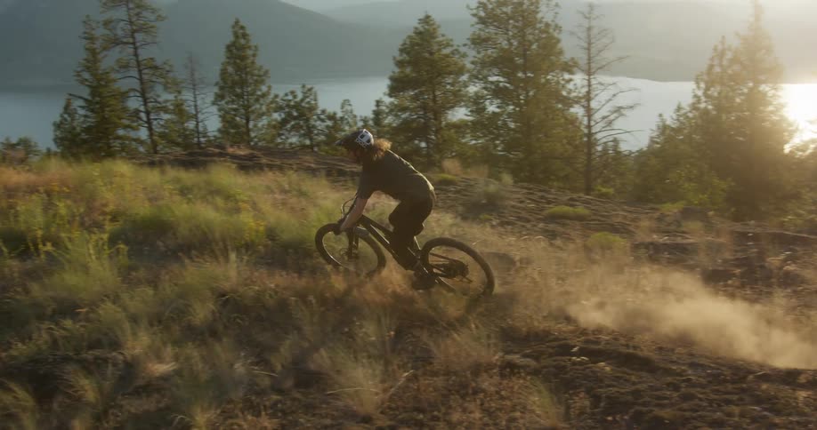 The man goes downhill on the mountain with his bike