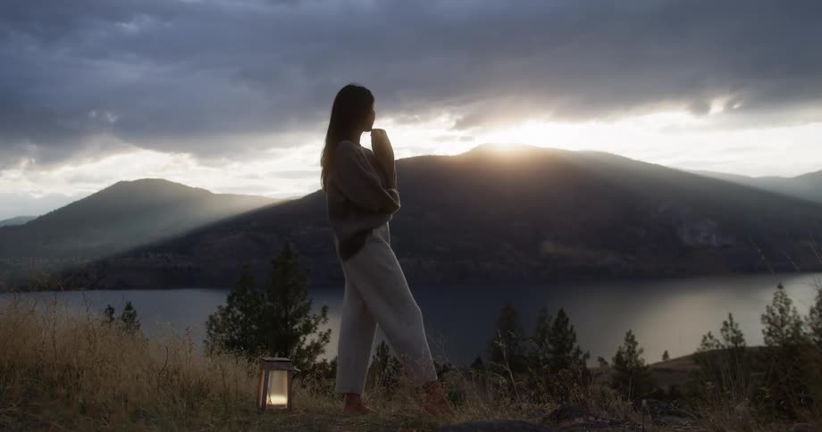 A woman is watching the sun rise behind the mountain