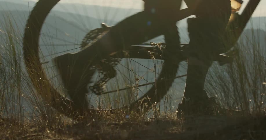 A person pushes their bike on the mountain top
