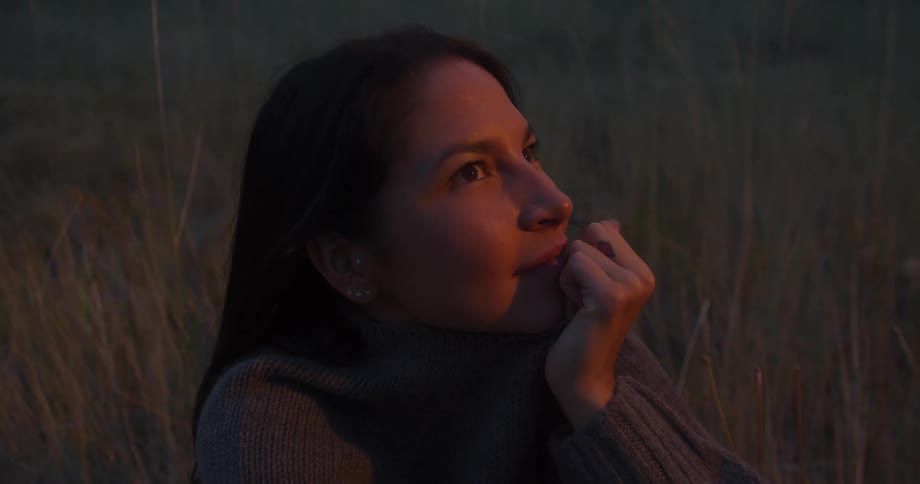 A woman smiles while sitting on the grass