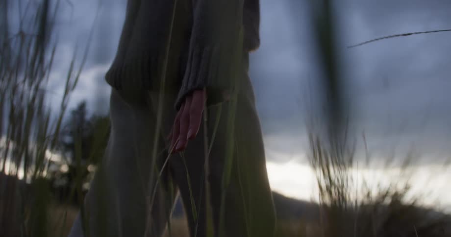 A female walking in a field carrying a lantern