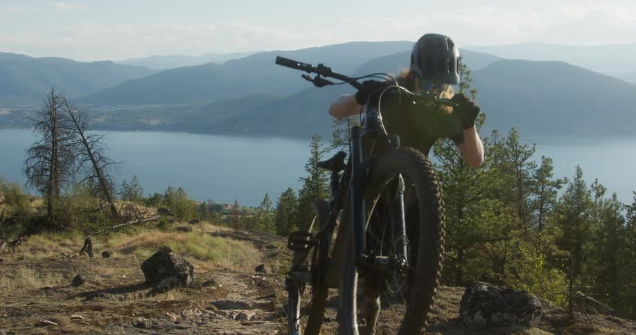 Woman with a mountain bike walking up a mountain