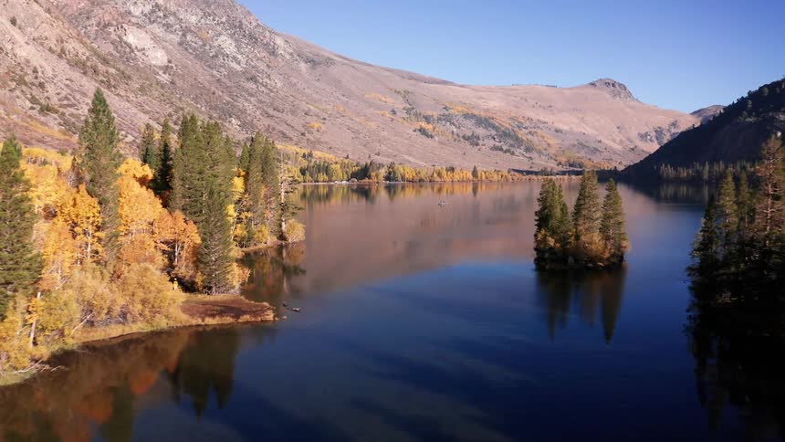 A calm lake winds through golden autumn trees beneath rugged mountain slopes at Silver Lake, California
