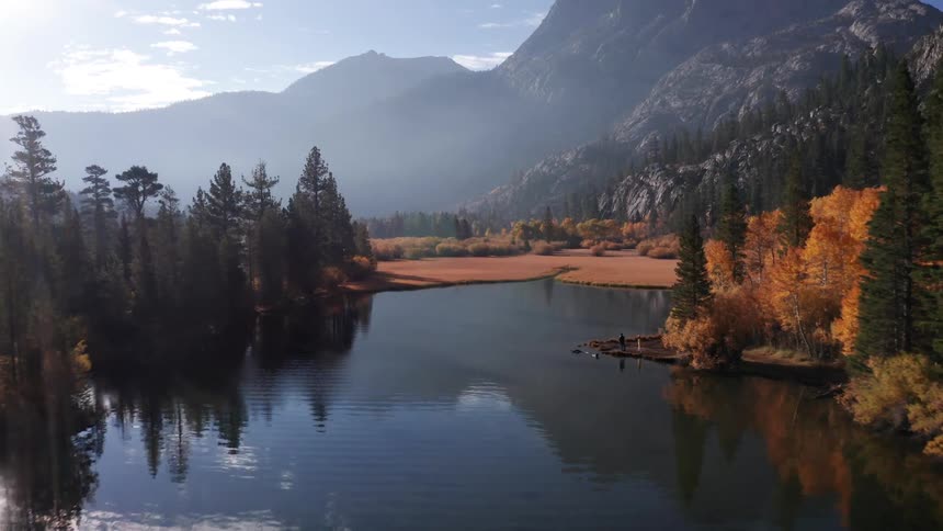 A calm mountain lake surrounded by autumn colored trees and towering rocky peaks at Silver Lake, California