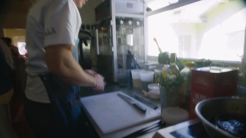 Man in apron and cap at restaurant sink