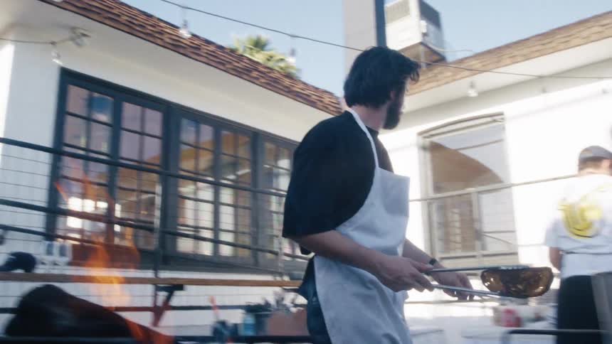 Chef prepares food at an outdoor kitchen during daytime