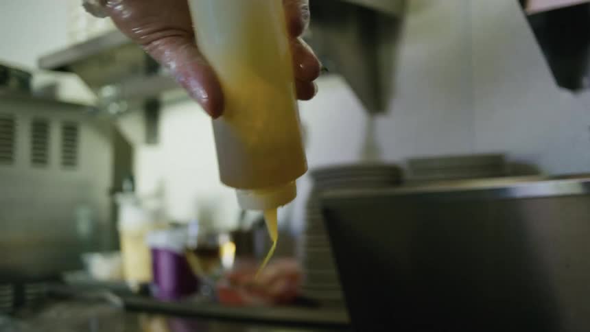 Person holding a clear bottle of seasoning and pouring it