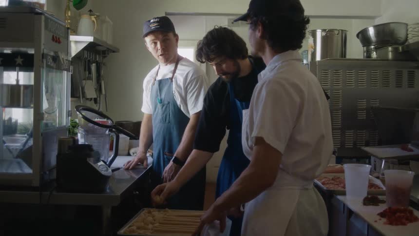 Three male chefs in aprons talking to each other