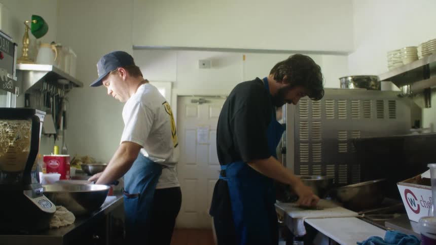 Two men cooking with aprons in a restaurant kitchen