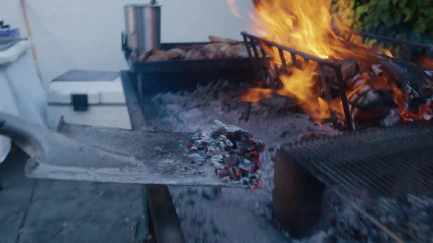 Person with a shovel taking out burnt coal and placing it to the side