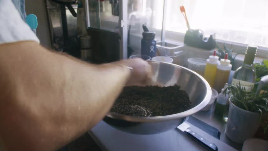 Person stirring a spice in a metal bowl