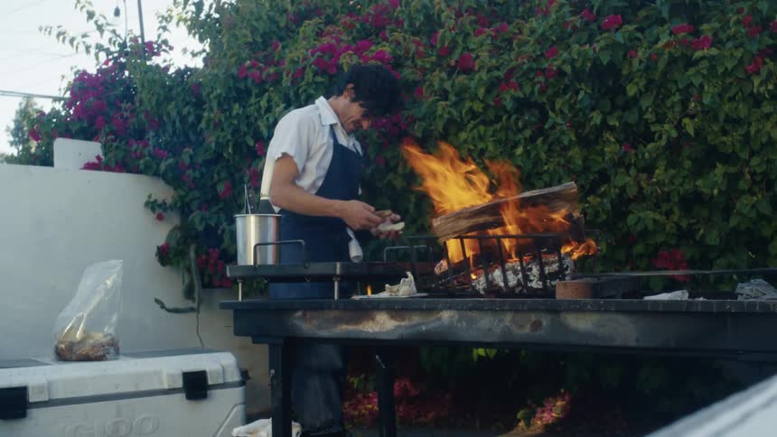A man prepares food at a fire