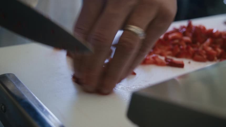 Close up of a male chef chopping strawberries on a counter top in kitchen during daytime