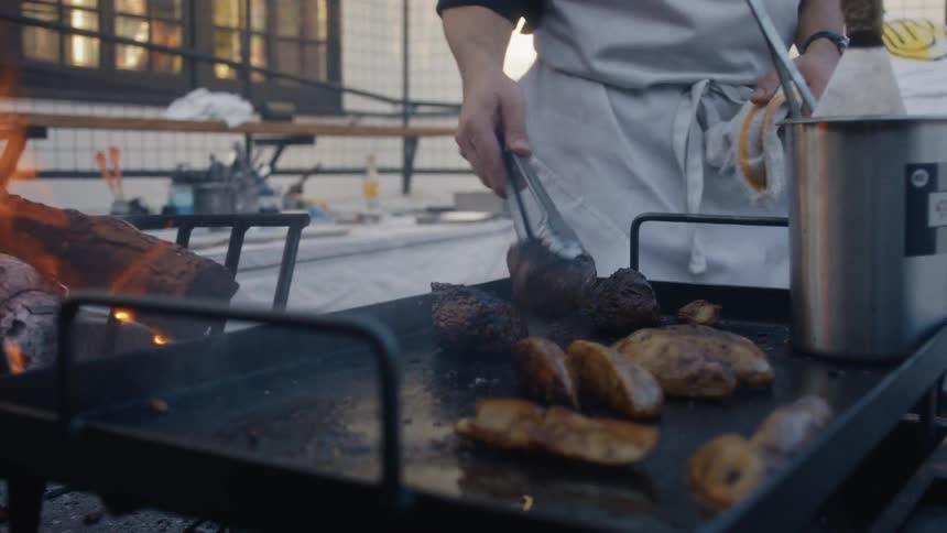 The chef flips the steaks on the grill