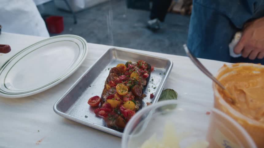 A freshly prepared bruschetta topped with seasoned cherry tomatoes is served on a metal tray