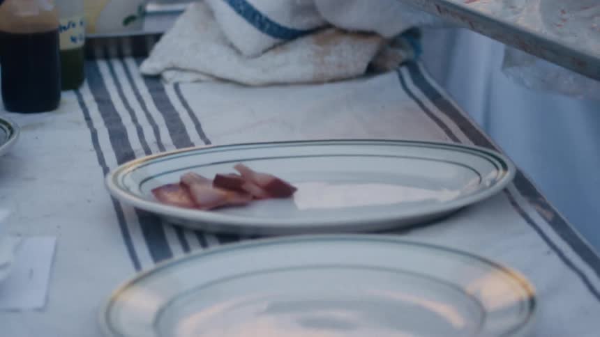 Person with gloves placing slices of meat on a plate