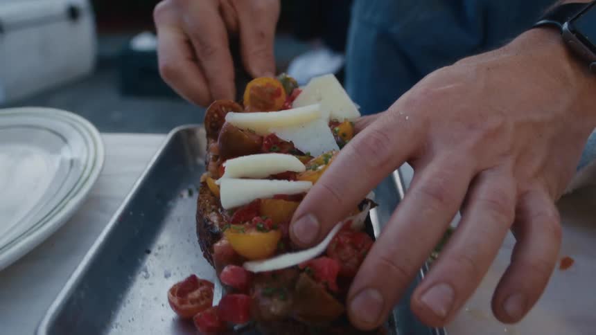 A man is plating food on a dish in a kitchen