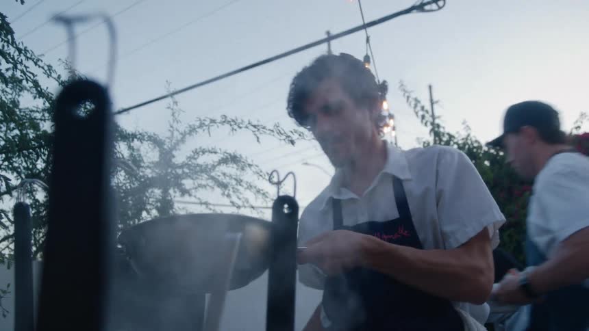 Chef cooks in an outdoor kitchen during dusk