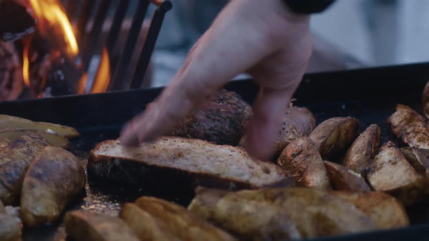 The man presses the food on the grill