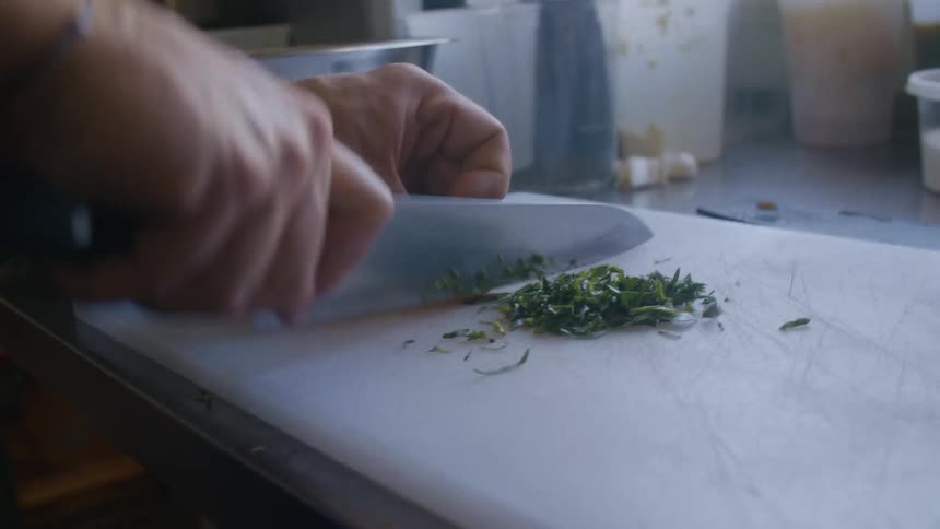 The man is chopping vegetables on the cutting board