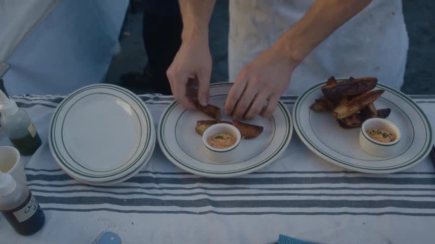 Person in white apron in a restaurant assembling dishes
