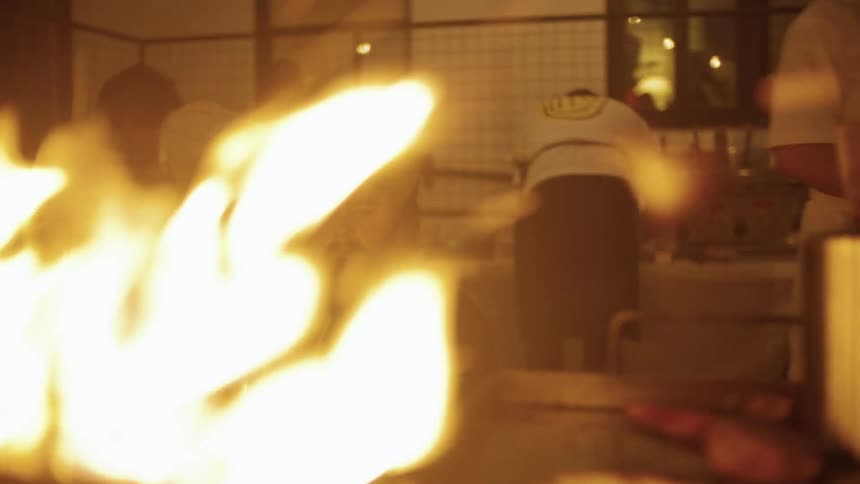 The cook is stirring the fire on the grill