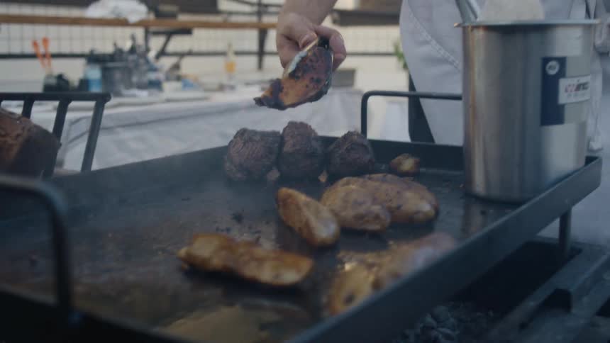 A man is flipping food on the grill with tongs