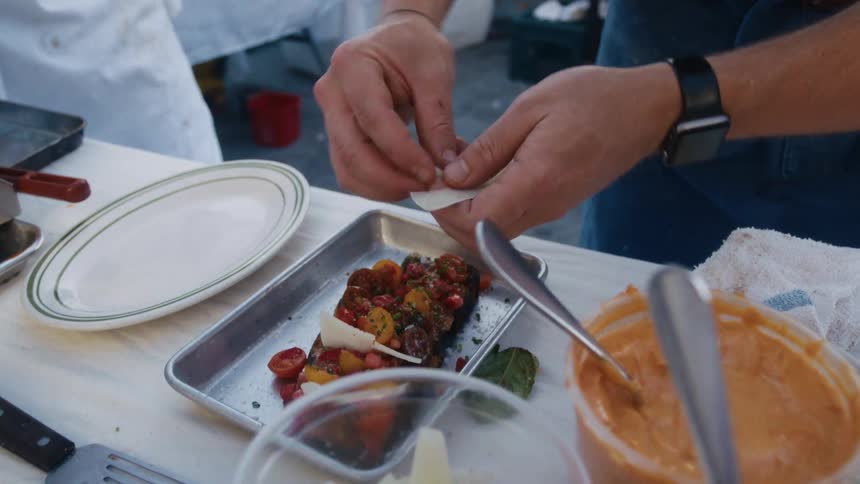 Person arranges food ingredients onto a tray by hand