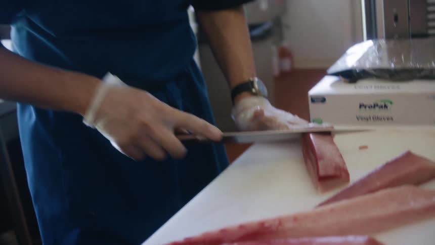 The man is cutting the meat on the cutting board
