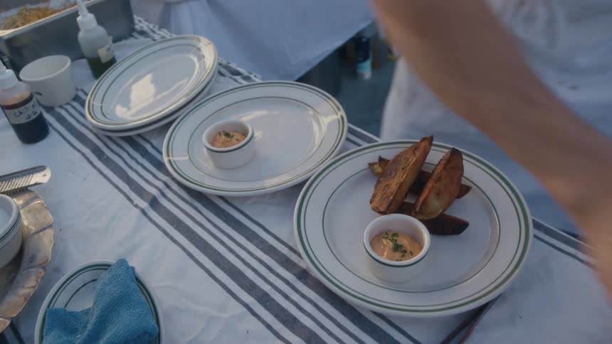 The man is placing food on the dish