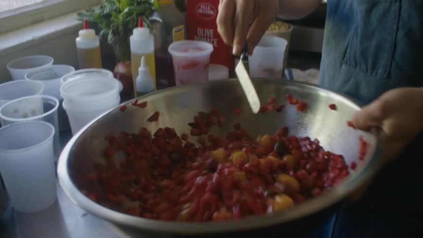 The cook is tossing the food in the bowl and mixing it