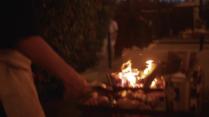 Man grilling barbecue outdoors at night on a griddle